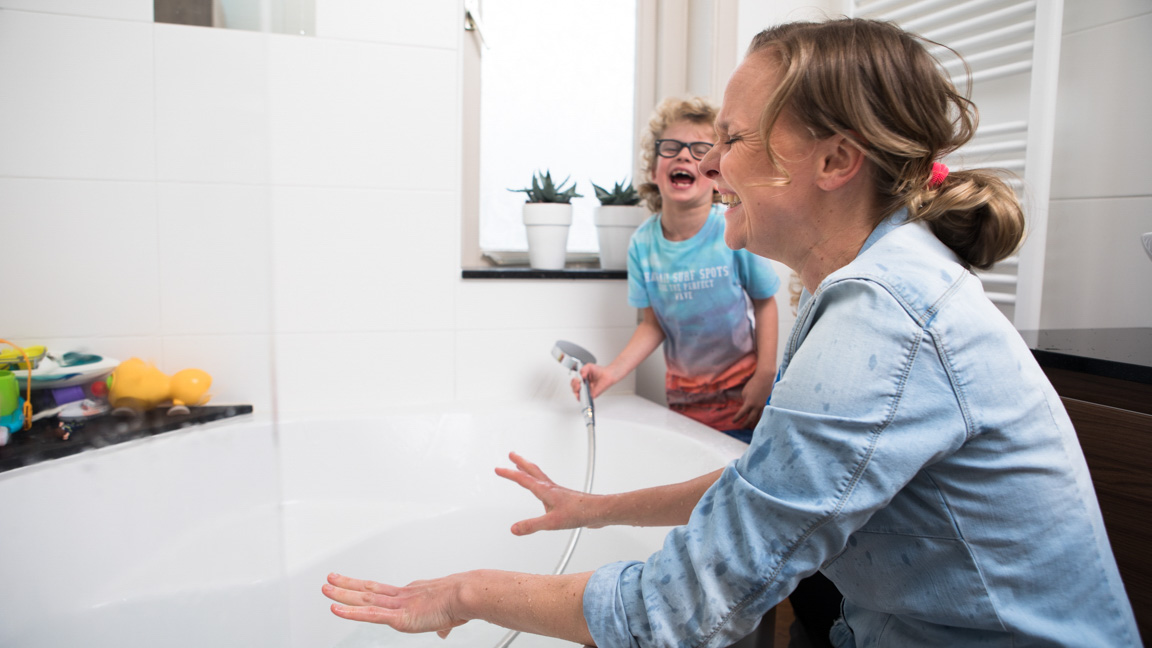 Moeder en zoon spelen met water bij bad
