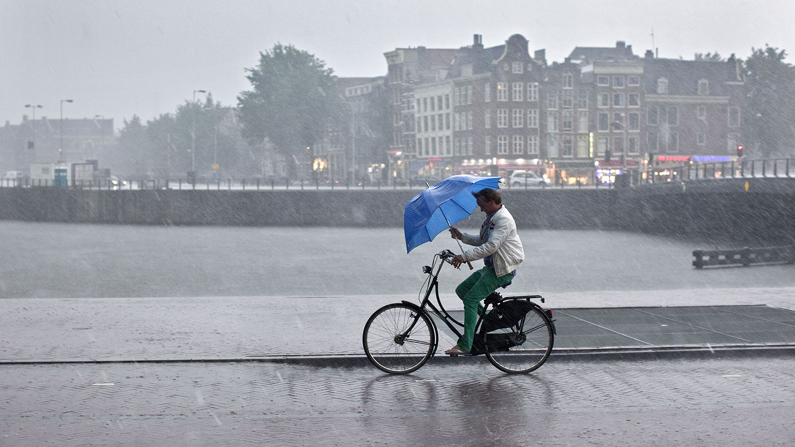 Man met paraplu in de regen op de Oosterdokskade Amsterdam