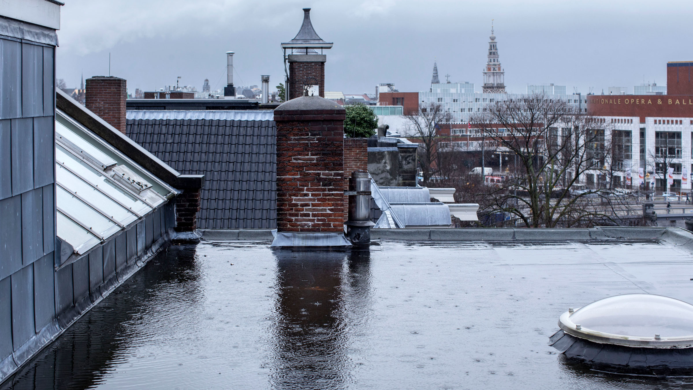 Regen valt op een plat dak bij de Amstel